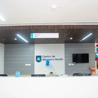 gynecologist and obstetrician in gomti nagar, lucknow, stands in a white medical coat having 'Max Hospital Logo' on it and standing with crossed arms.